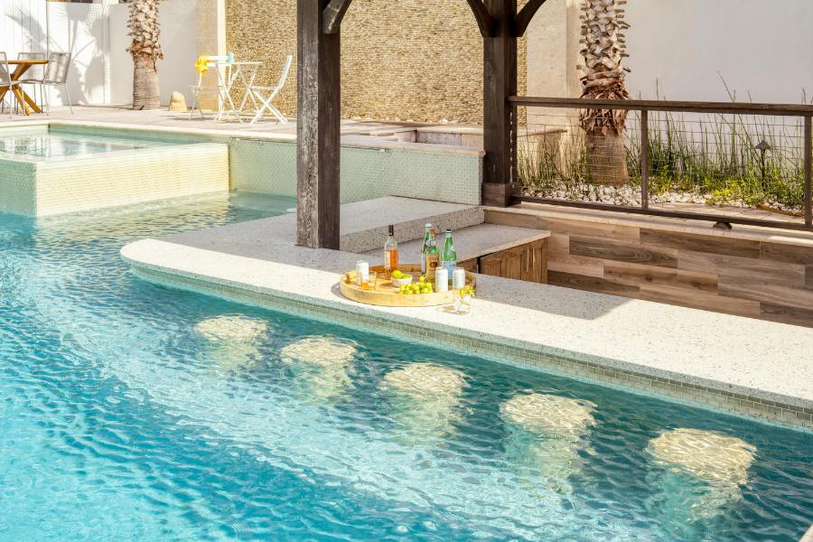swim up bars with 6 seats. a slab of smooth white stone bar with cocktails on top