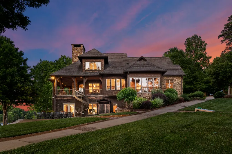 big bricked 3 story mansion with illuminating night lights by the woods